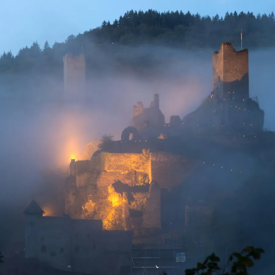 Manderscheider Burgen im Morgennebel mit beleuchteter Burgruine
