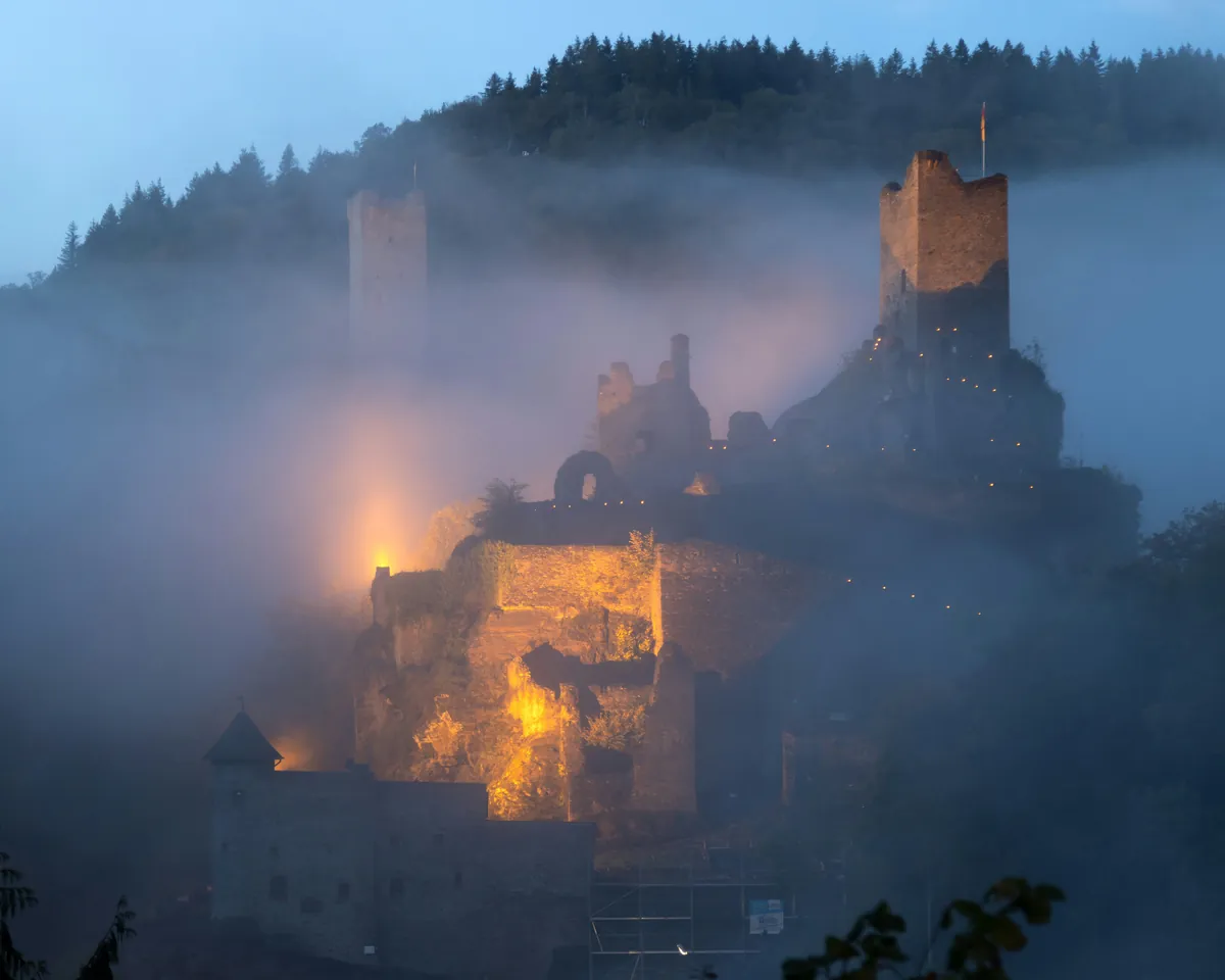Manderscheider Burgen im Morgennebel mit beleuchteter Niederburg